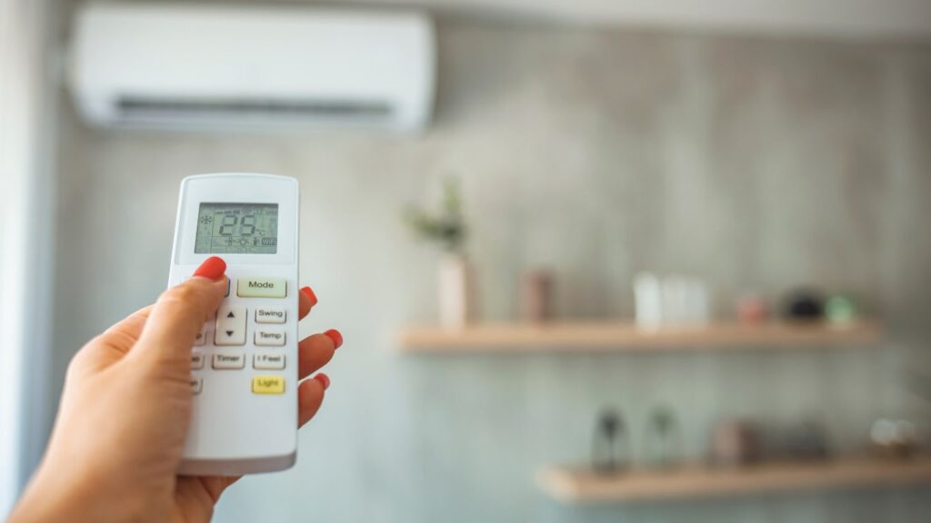 Klímaberendezés távirányítóval, amelyet egy modern nappaliban használnak a hőmérséklet szabályozására.